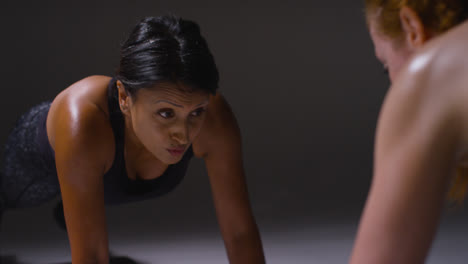 Close-Up-Studio-Shot-Of-Two-Mature-Women-Wearing-Gym-Fitness-Clothing-Doing-Plank-Exercise-Together